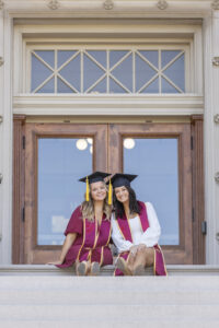 A pair of graduating seniors pose at Beardshear Hall.